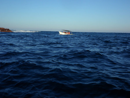 A small boat amidst the dark-blue oceanの写真素材
