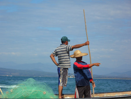 Two traditional fishermen with hats and nets on a boat at the Pacific coast of Mexicoのeditorial素材