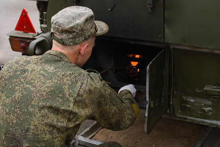 A soldier lights a fire in the field kitchen for cooking