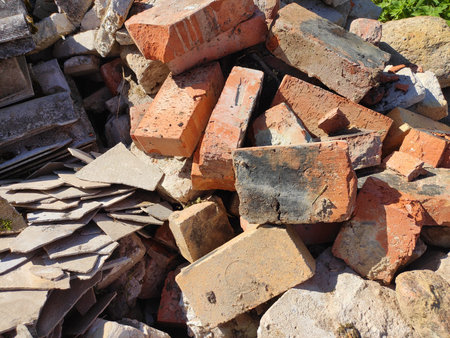 Old broken red bricks lie in a mess outdoors