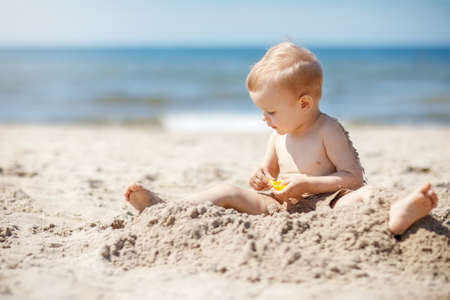 Child playing on Baltic sea beach. Little boy digging sand at sea shore. Family summer vacation. Kids play with water and sand toys. Travel with young children.の写真素材