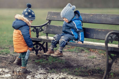 Two little boys is covered in mud and dirt in a swamp at the park. He is very unclean as he learns about nature and outdoors. Both children are happy they don't care to get smeared.の写真素材