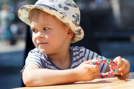 A child with a hat, in his hands candy - a clock, a dark blue background.の写真素材
