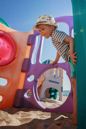 A cute smiling boy playing on an outdoor playground on the beachの写真素材