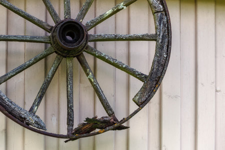 Vintage broken, rotten wooden carriage wheel on the wooden wall of the houseの写真素材