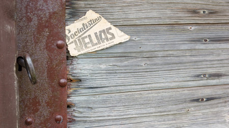 Lock, key, keyhole and piece of old newspaper on old wooden door. The old piece of the newspaper contains the inscription in Lithuanian language - "socialist path"の写真素材