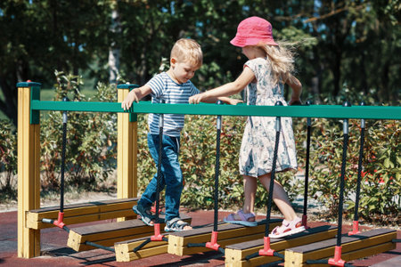 The boy and girl meet each other on a monkey bridge at a city children's playground.の写真素材