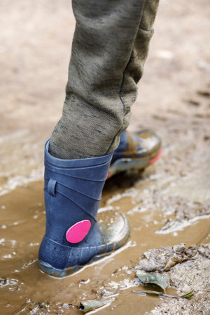 Dirty little boy rubber boots in blue. Waterproof footwear for agricultural activity, gardener working, autumn concept.の写真素材