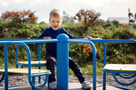 Portrait of cheerful boy sitting on merry-go-round. Concept of child development, sports and education.の写真素材