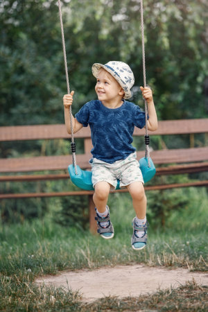 Little boy swinging high, smiling and looks to his mother. The child is very happy he likes to swing.の写真素材