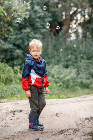A little boy walks in the fresh air after rain, the child wears waterproof clothes.の写真素材