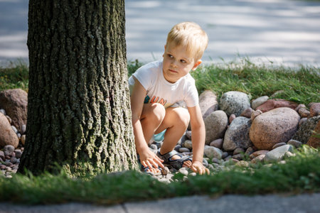 A child plays with pebbles in the city park. The concept of recreation, play and the development of children's motor skills. High quality photo.の写真素材