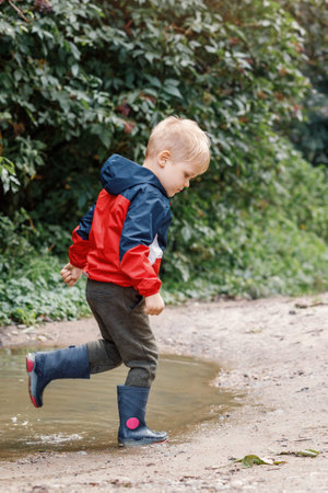 Little boy splashing in a mud puddle, jumping into a puddle.の写真素材