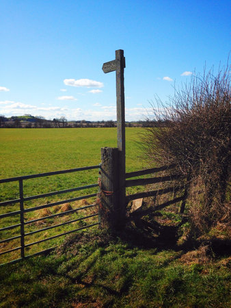 Footpath sign and rickety stile in Worcestershire UK. Sunny day and blue sky.の素材