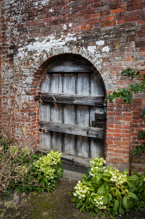 Old weathered wooden garden door in brick wall.の写真素材