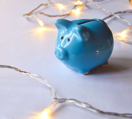 Photo of a blue piggy bank and lights on white backgroundの写真素材