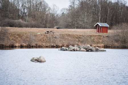 Landscape photo of a small red house and a lake during autumn season