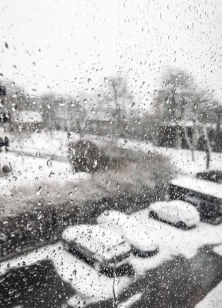 Photo of a window with water drops on during winter stormの写真素材