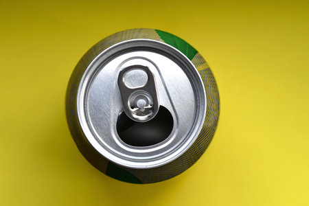 Overhead photo of a soda can or tin on yellow background