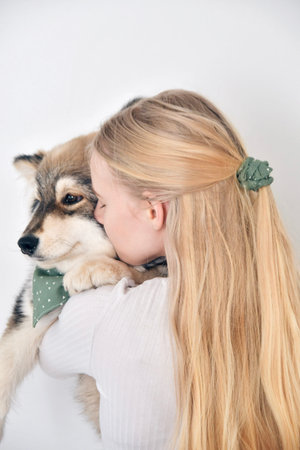 Photo of a young woman kissing a puppy Finnish Lapphund dog and wearing matching bandana and...