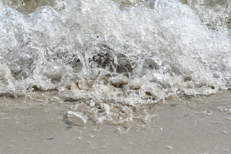 Photo of an ocean wave crashing in on shore on the beach