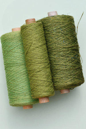 Photo of threads in different shades of green on bright background