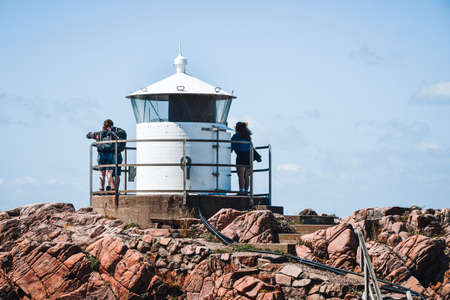 Photo of a lighthouse at the sea with people inの写真素材