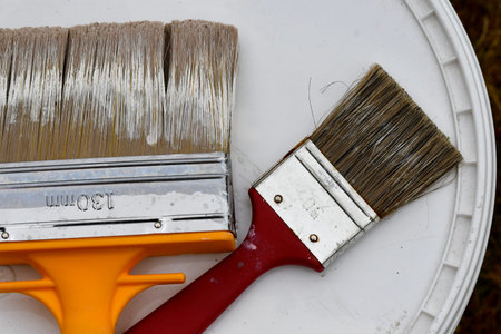 Closeup of paint brushes lying on top of paint bucket