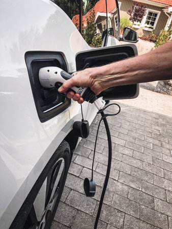 A man putting charger in his white electric car