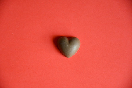 Photo of chocolate candy heart on red backgroundの写真素材