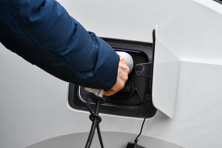 A man putting in charger cable in white electric car
