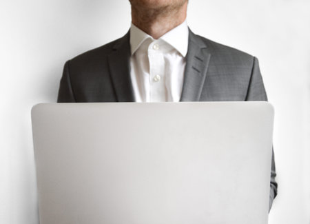 Businessman behind a laptop computer against white background