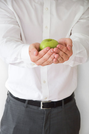Businessman in shirt and suit holding a green appleの写真素材