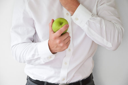 Businessman in shirt and suit holding a green appleの写真素材