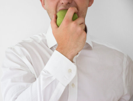 Businessman in shirt and suit eating a green apple