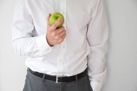 Businessman in shirt and suit holding a green appleの写真素材