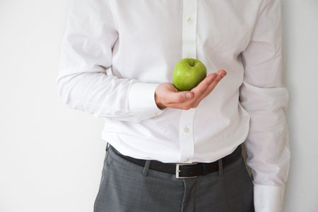 Businessman in shirt and suit holding a green appleの写真素材