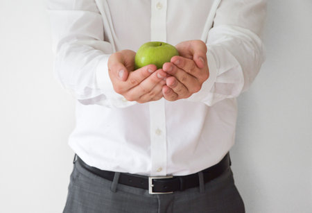 Businessman in shirt and suit holding a green appleの写真素材