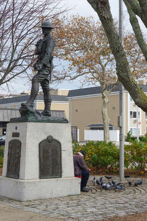 Rockaway Park, Queens, New York: An old man feeds pigeons beneath a statue honoring veterans.のeditorial素材