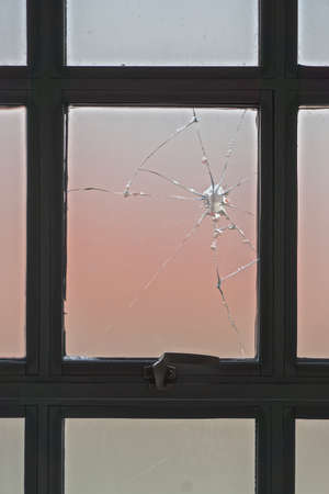 A broken window of opaque glass in a wrought iron frame.の写真素材