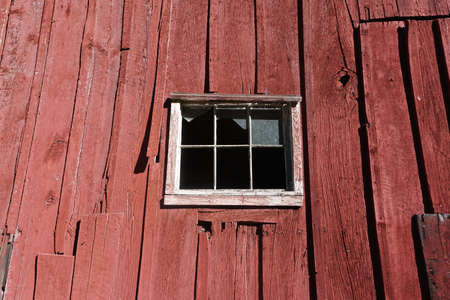 Pocono Mountains, Pennsylvania: The window of an abandoned red barn with broken glass and peeling red paint.の写真素材