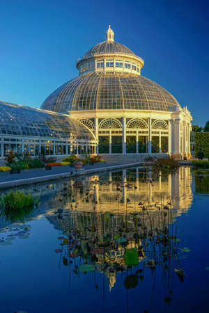 The Bronx, New York: The Enid A. Haupt Conservatory, 1902, at the New York Botanical Garden, reflected in an outdoor pool with water lilies.のeditorial素材