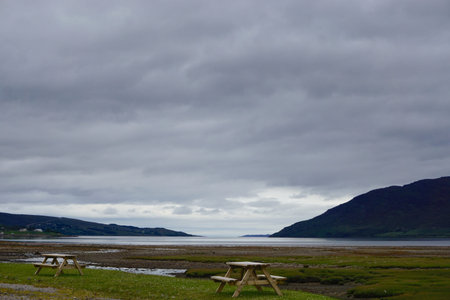 Picnic tables on a lawn next to the bog at  Dundonnell, Scotland. View of Little Loch Broom is in...
