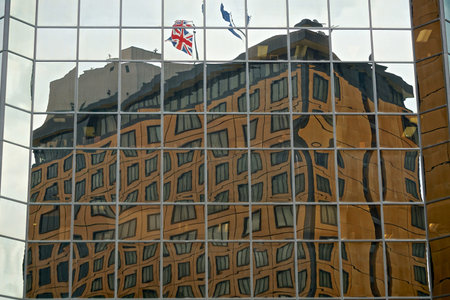 Anchorage, Alaska: Building with flags on its roof is reflected in the glass facade of another...