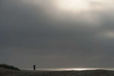 Assateague National Seashore, Virginia: A solitary photographer captures sunrise on the Atlantic Ocean.の写真素材