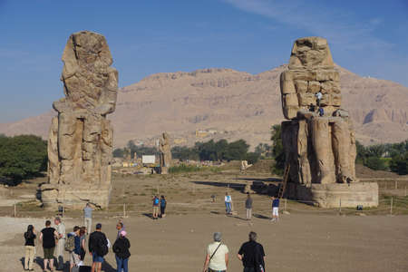 Luxor, Egypt: Tourists visit the Colossi of Memnon (1350 BC), two massive statues of the Pharaoh Amenhotep III, who reigned during the 13th Dynasty.のeditorial素材