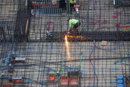 New York, New York: Sparks fly as a worker uses a rotary saw to cut reinforcing iron rods at a...
