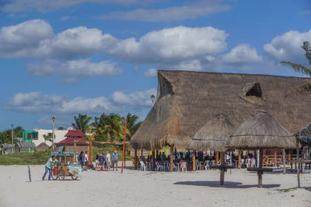 Celestun, Yucatan, Mexico: A vendor pushes his cart past customers relaxing at a restaurant on the beach.のeditorial素材