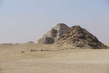Saqqara, Egypt: The pyramid of Userkaf (right) with the step pyramid of Djoser, undergoing restoration, in the background.のeditorial素材