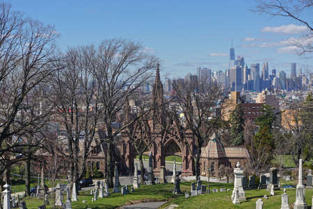Brooklyn, New York: One World Trade Center (aka Freedom Tower) and the Manhattan skyline is seen in the distance over the Gothic entrance to historic Green-Wood Cemetery, founded in 1838.の写真素材